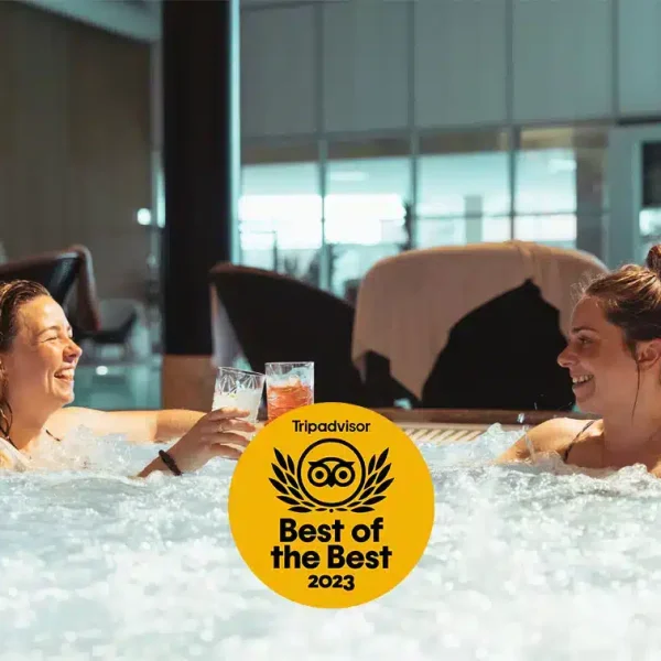 Glade veninder i spabad med drink i hånden